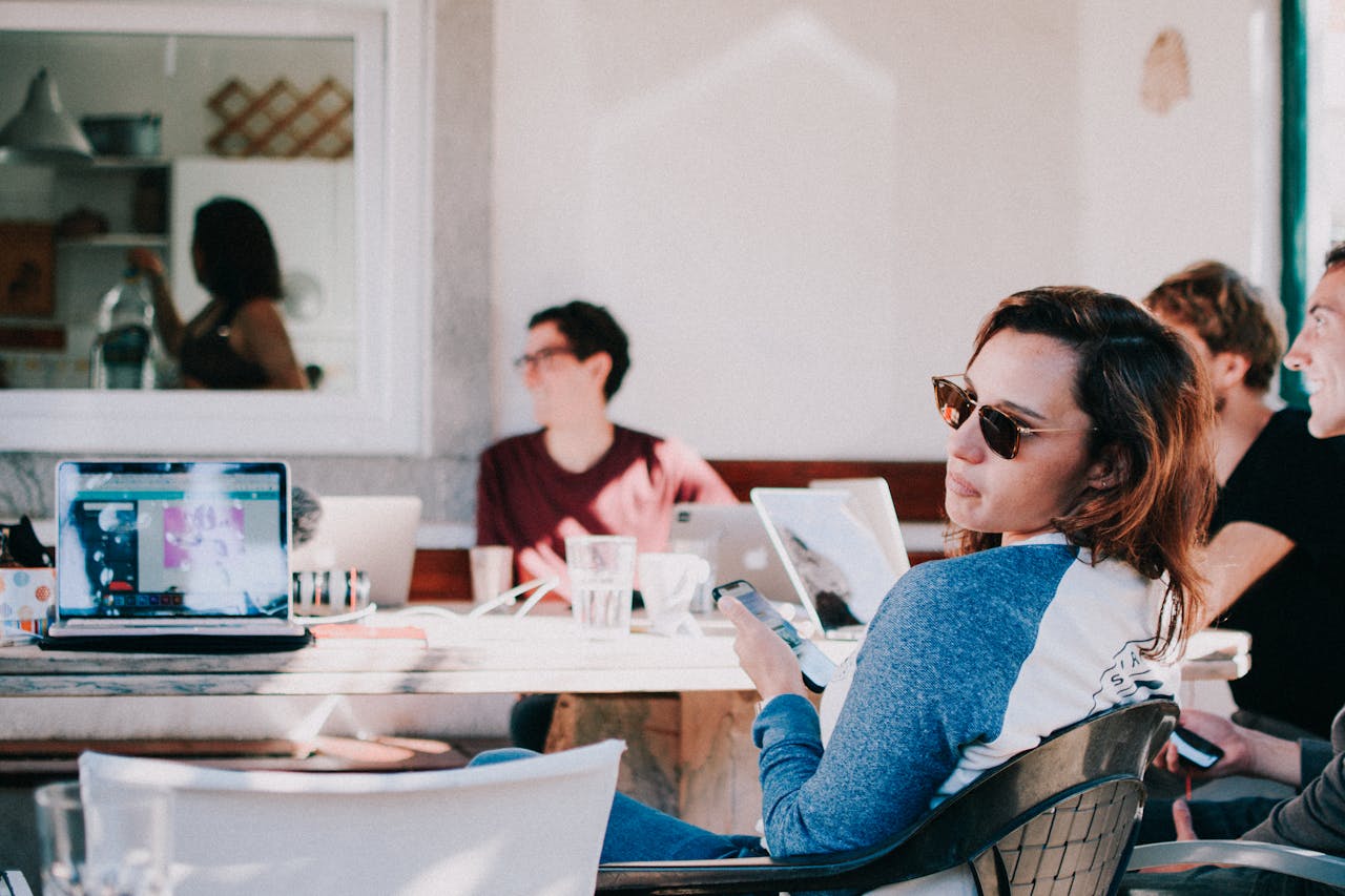 Young adults in a relaxed co-working environment, using laptops and smartphones.